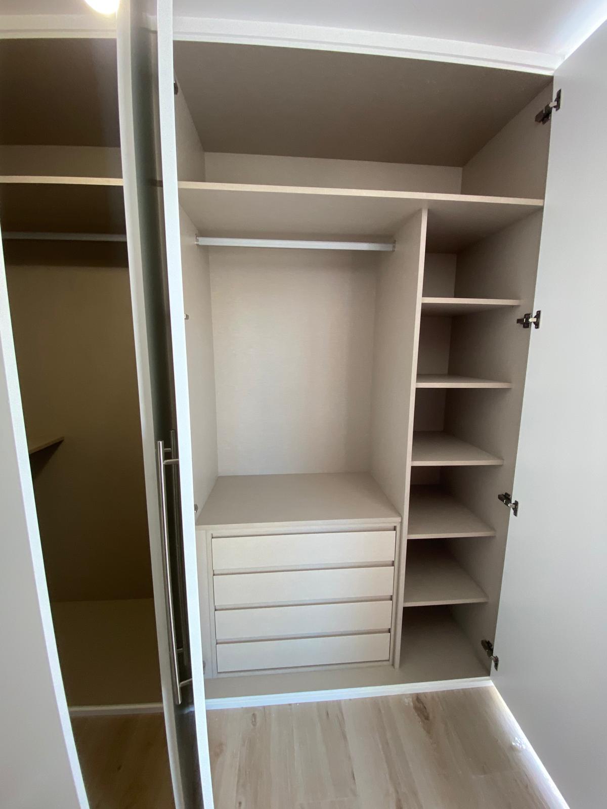 Interior de armario con barra de colgar, cajonera y columna de baldas